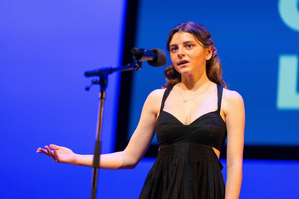 A student recites on stage.