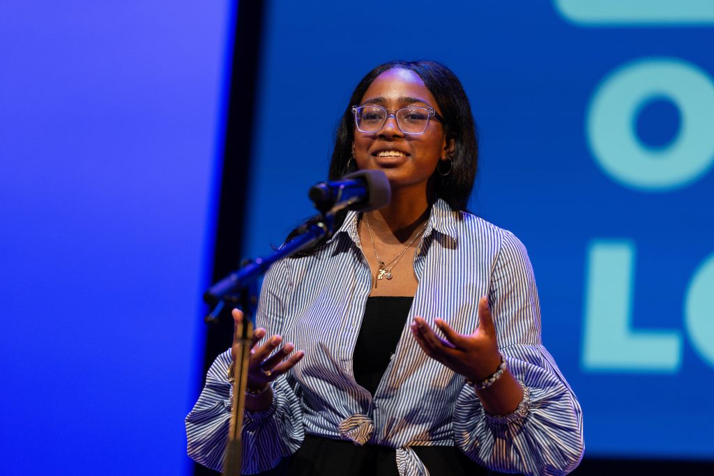 Young person recites at a microphone.